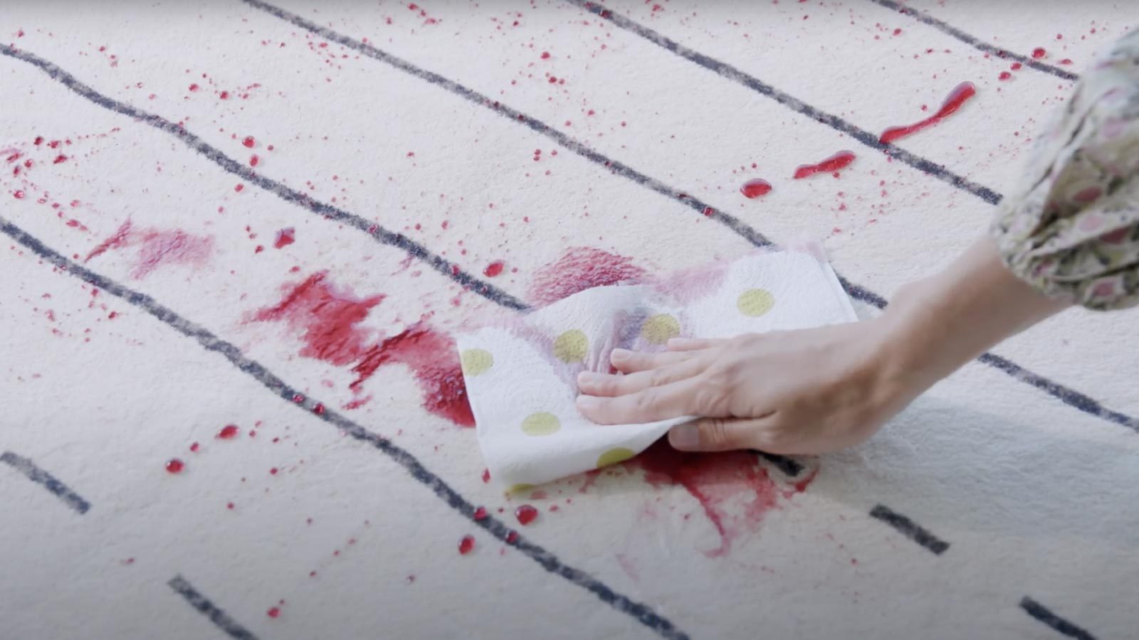 Una mano tampona una macchia rossa sul tappeto