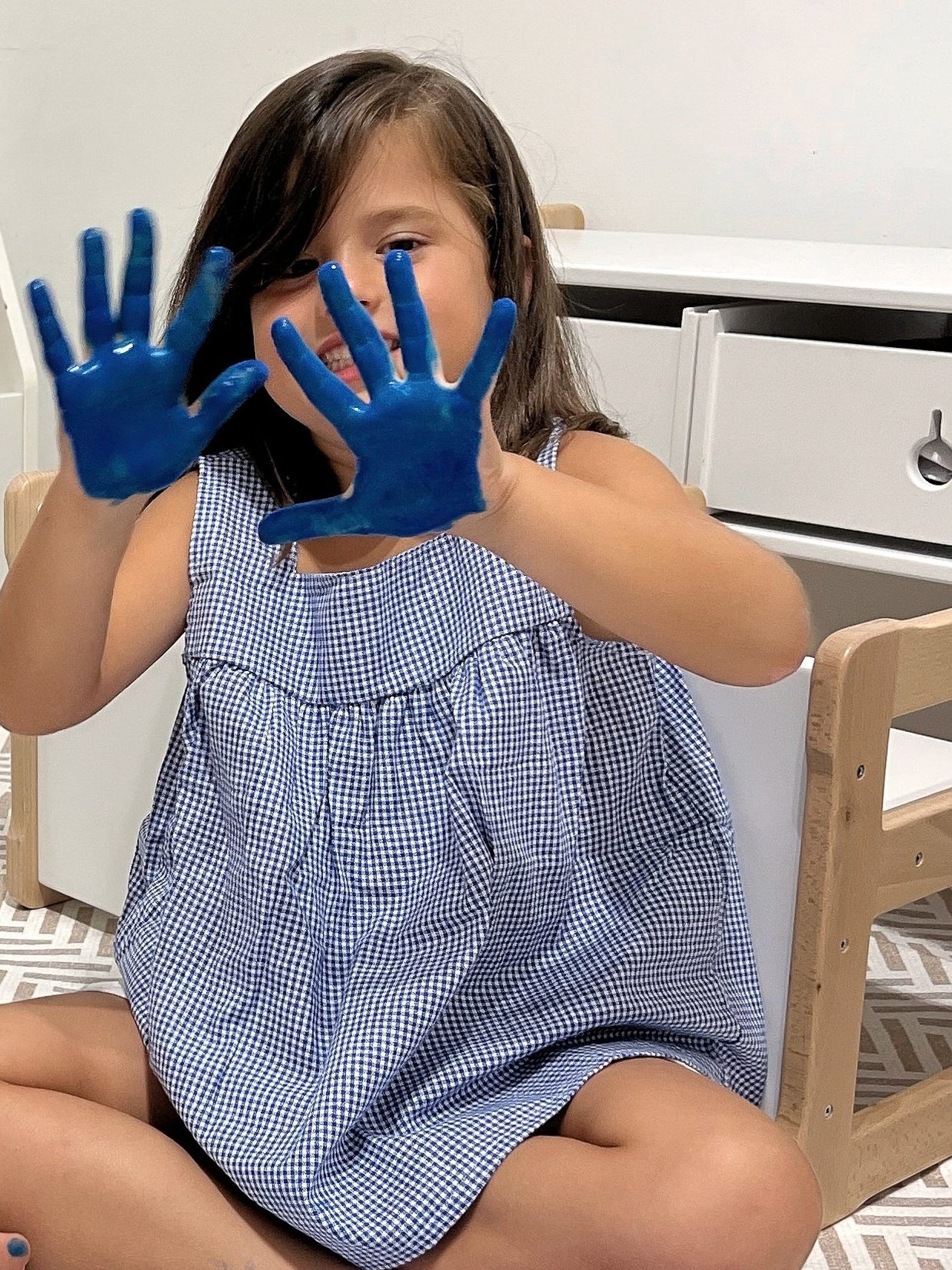 Una bambina con le mani sporche di tempera blu