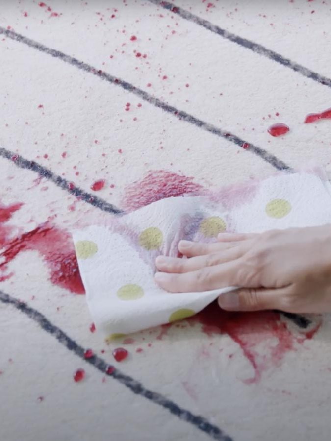 Una mano tampona una macchia rossa